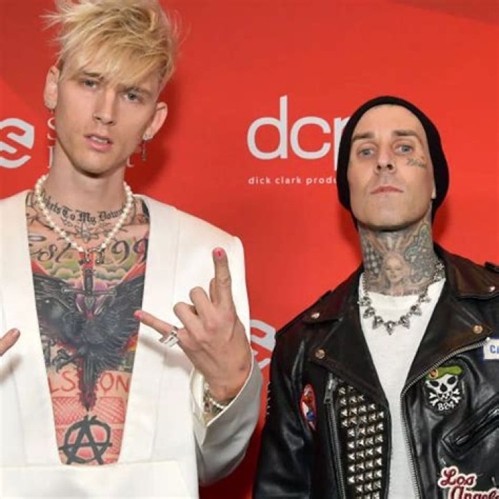 Machine Gun Kelly and Travis Barker holding signs